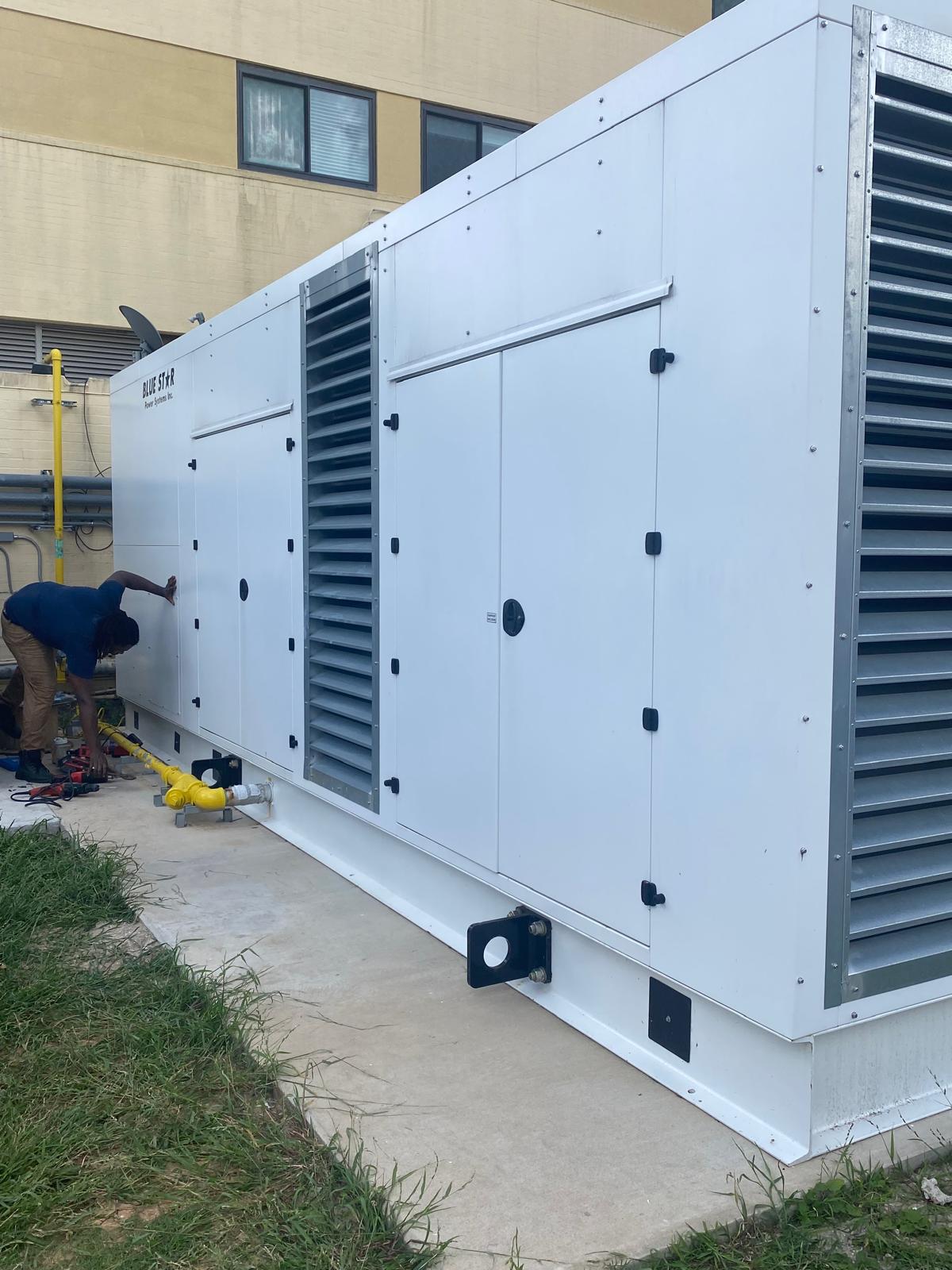 Large outdoor generator with a technician working alongside it